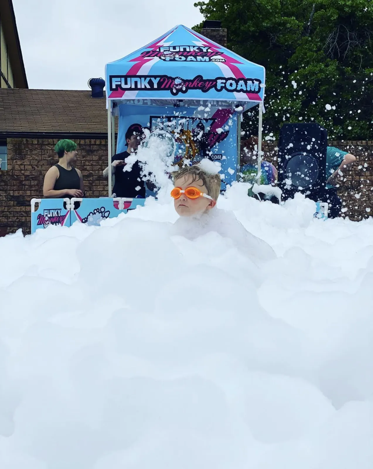 Kids buried in mountains of foam in front of the Funky Monkey Foam tent
