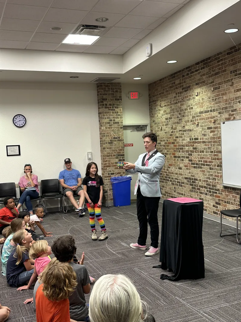 Joe Coover performing for kids seated on the floor of a library program room