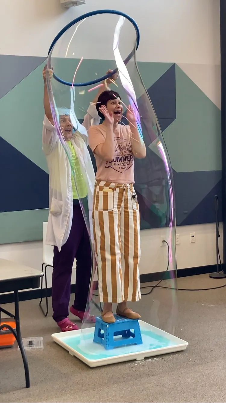 A volunteer standing inside a giant bubble during the Professor Buckets Bubble Show